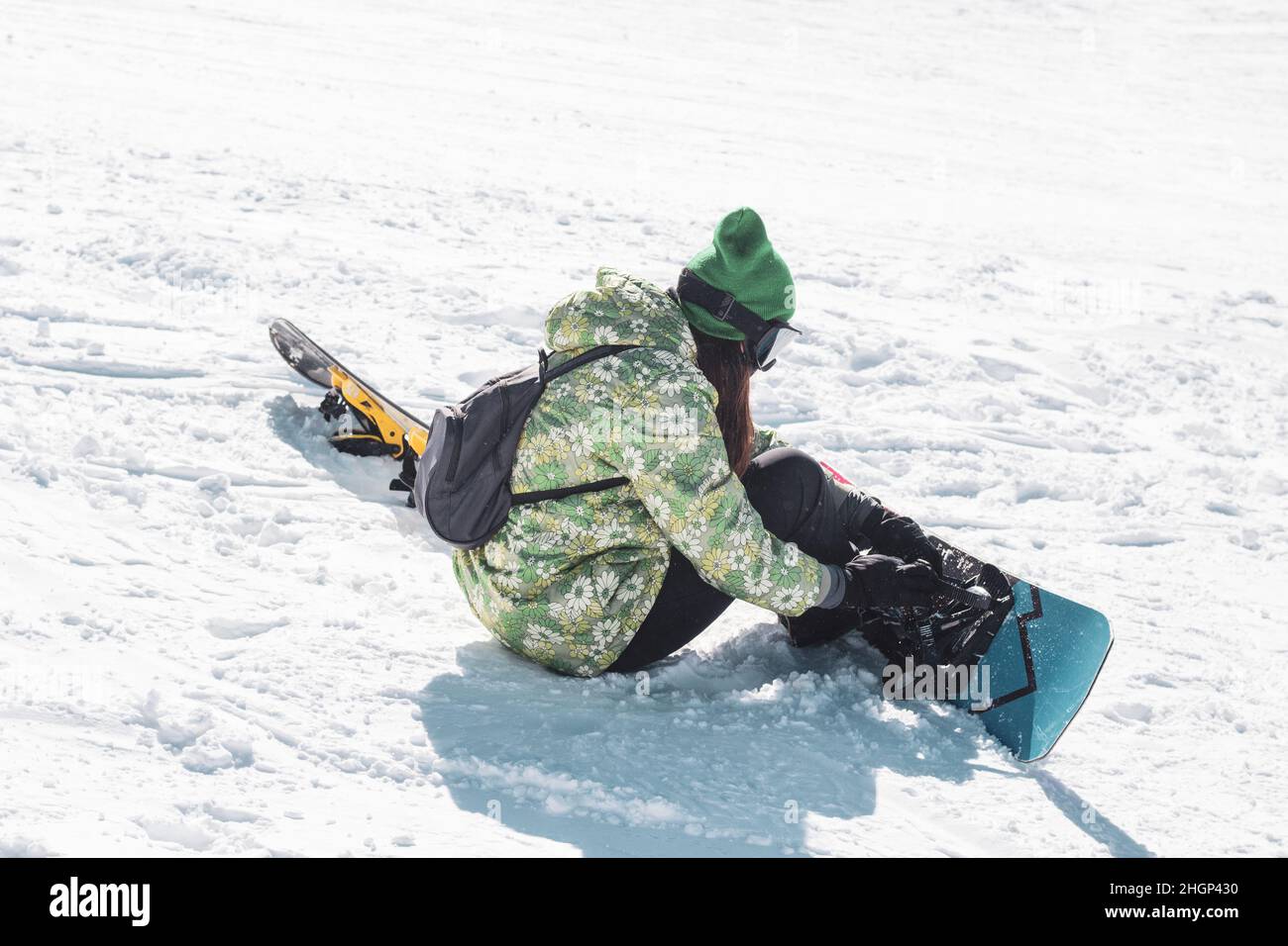 Snowboarder woman on the snow. Snowboarder sitting on the and getting ready to slide. Recreational concept. Stock Photo