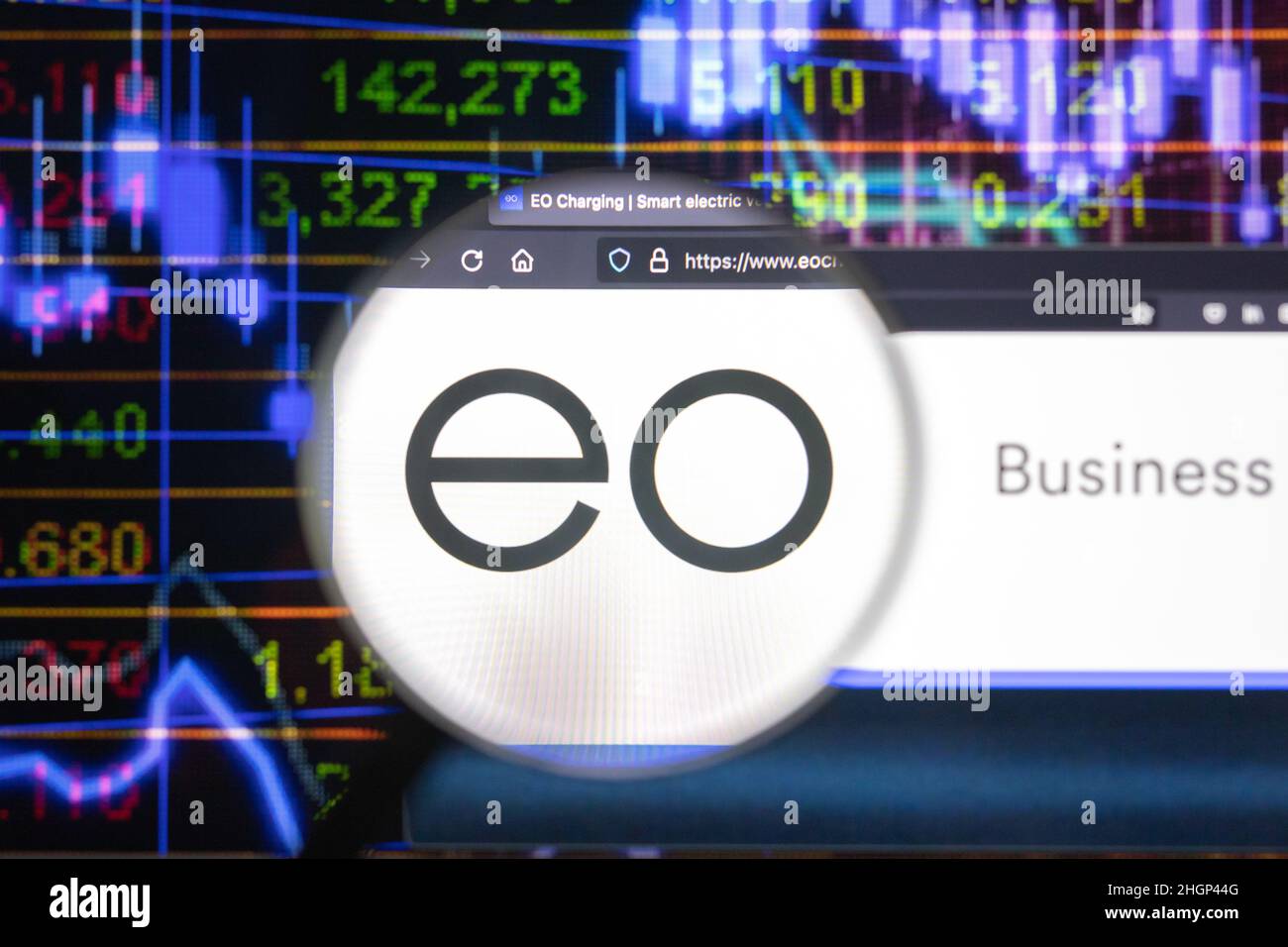 EO company logo on a website with blurry stock market developments in the background, seen on a computer screen through a magnifying glass. Stock Photo
