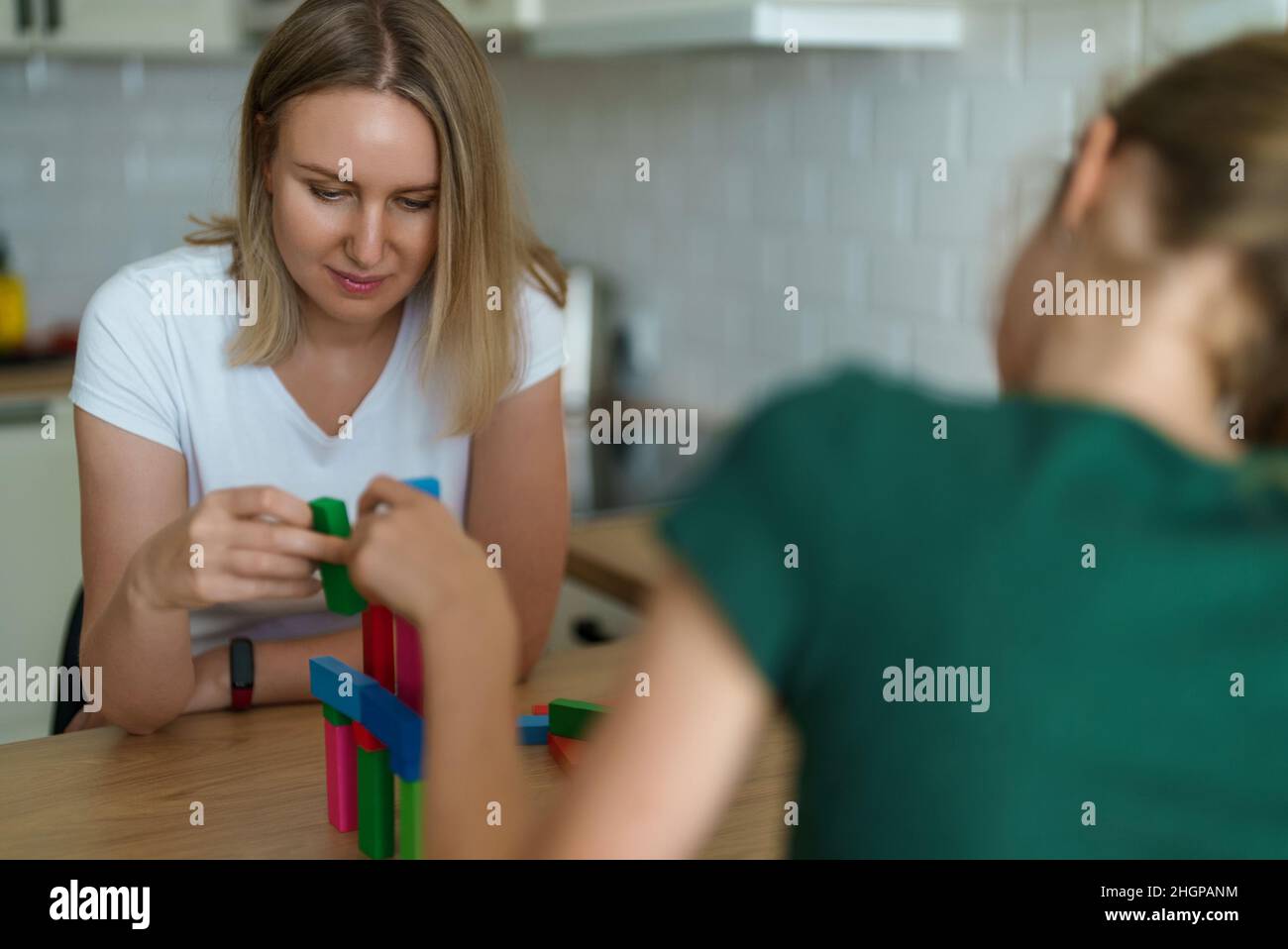 Woman and daughter playing jenga tower game at home. Stock Photo