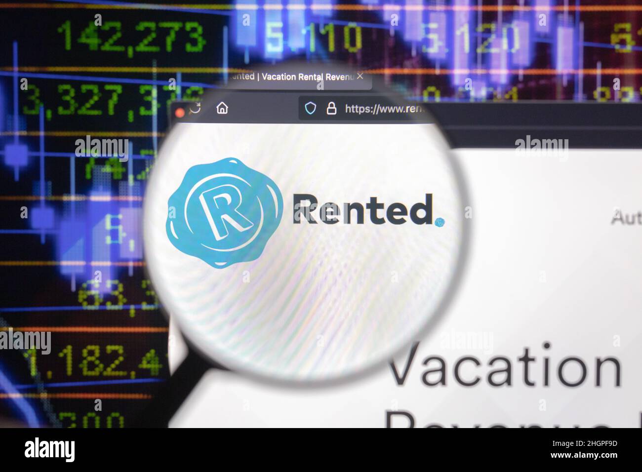 Rented company logo on a website with blurry stock market developments in the background, seen on a computer screen through a magnifying glass. Stock Photo