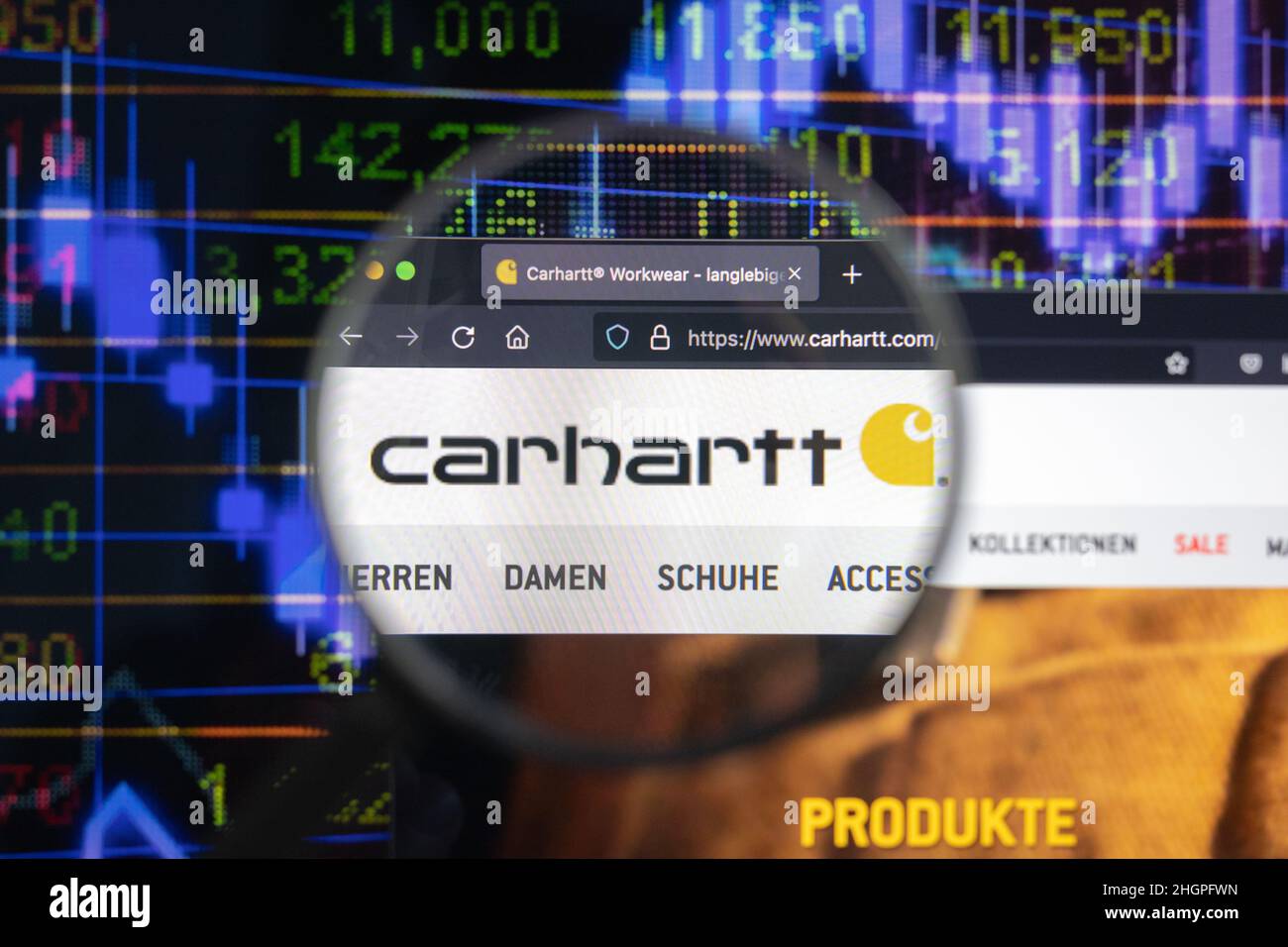 Carhartt company logo on a website with blurry stock market developments in the background, seen on a computer screen through a magnifying glass. Stock Photo