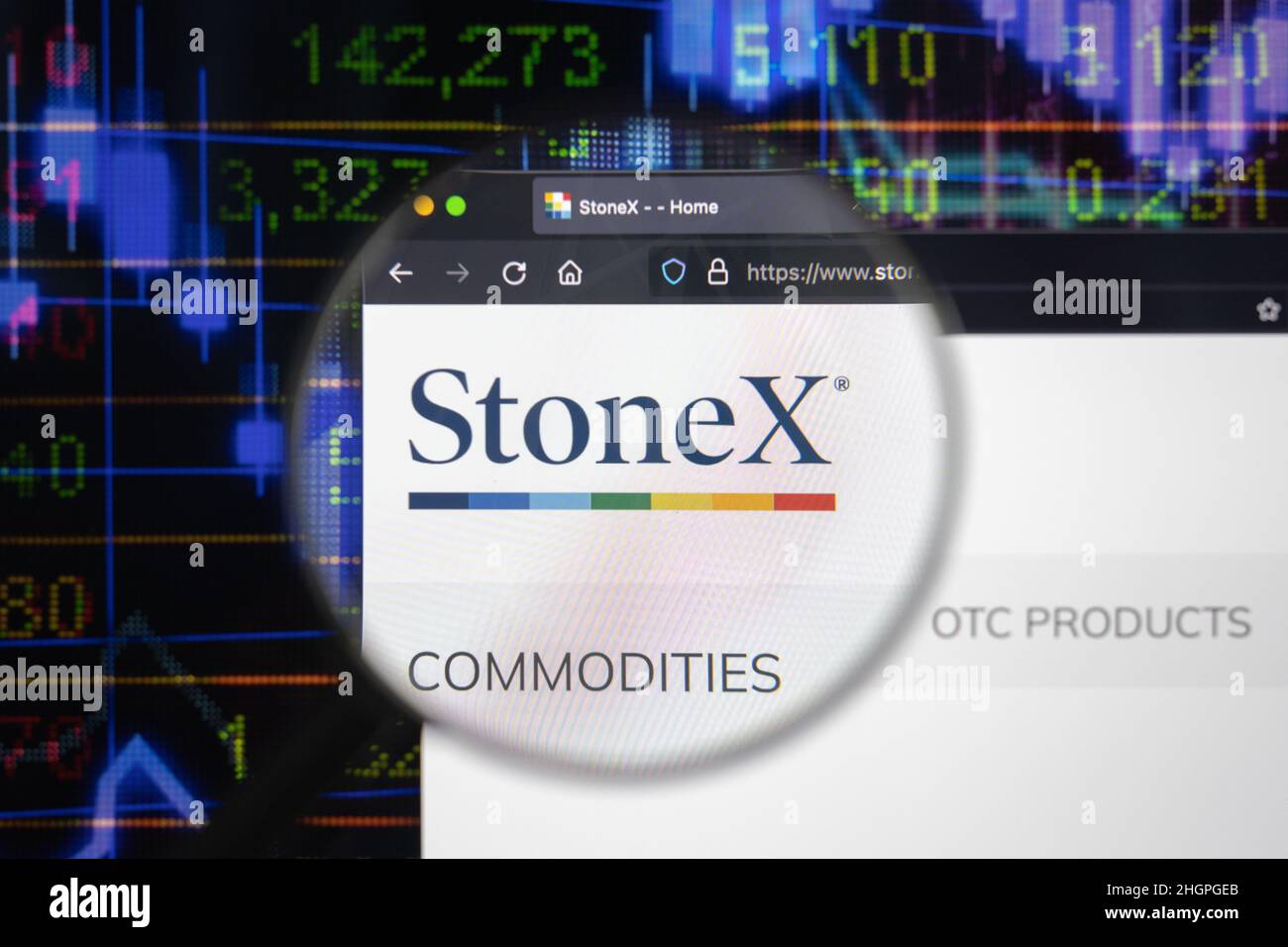Stone x company logo on a website with blurry stock market developments in the background, seen on a computer screen through a magnifying glass. Stock Photo