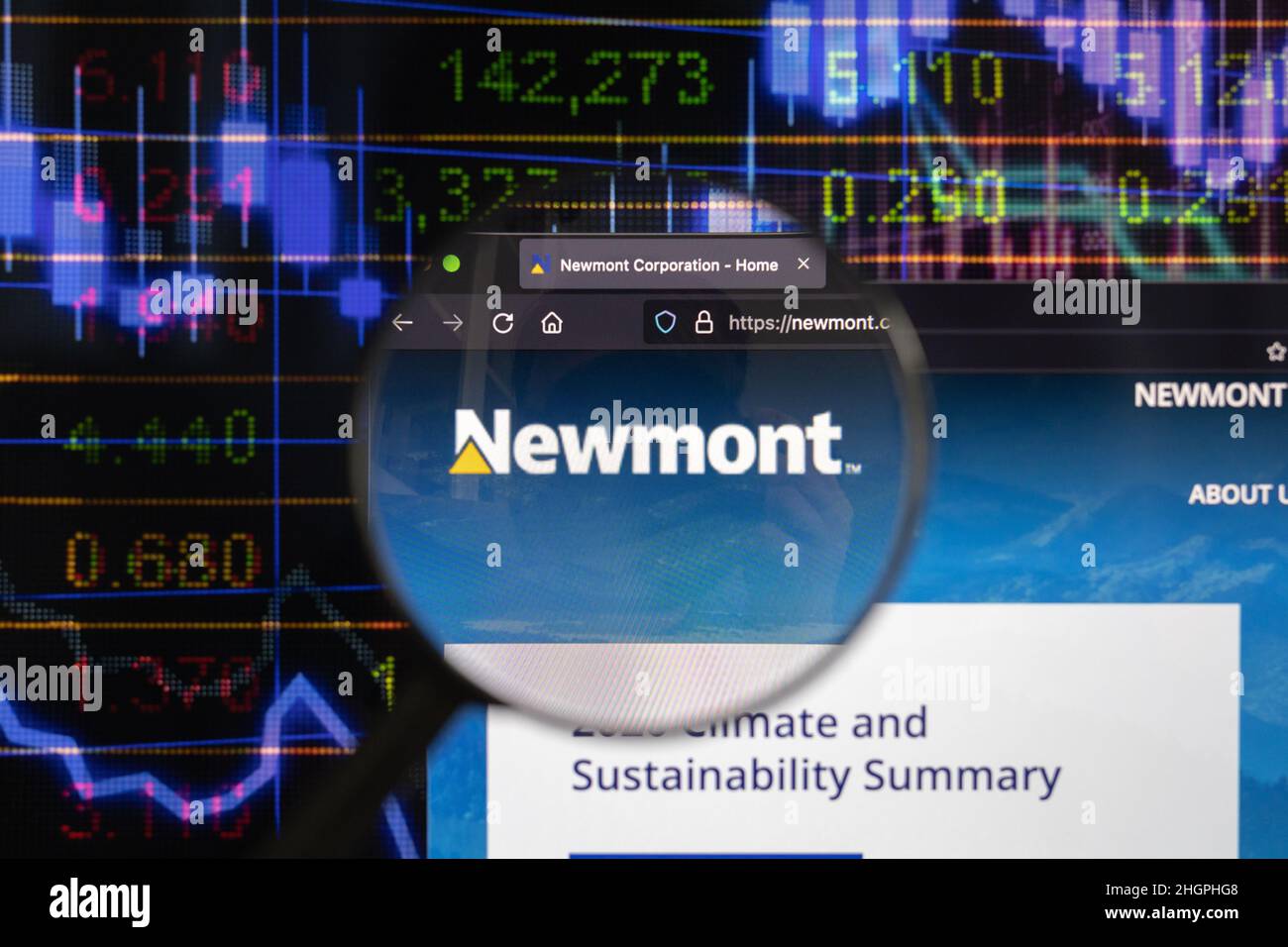 Newmont company logo on a website with blurry stock market developments in the background, seen on a computer screen through a magnifying glass. Stock Photo