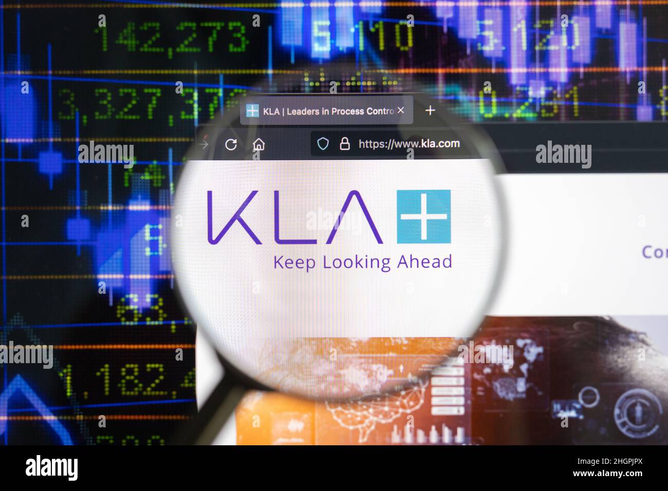 KLA corporation logo on a website with blurry stock market developments in the background, seen on a computer screen through a magnifying glass. Stock Photo