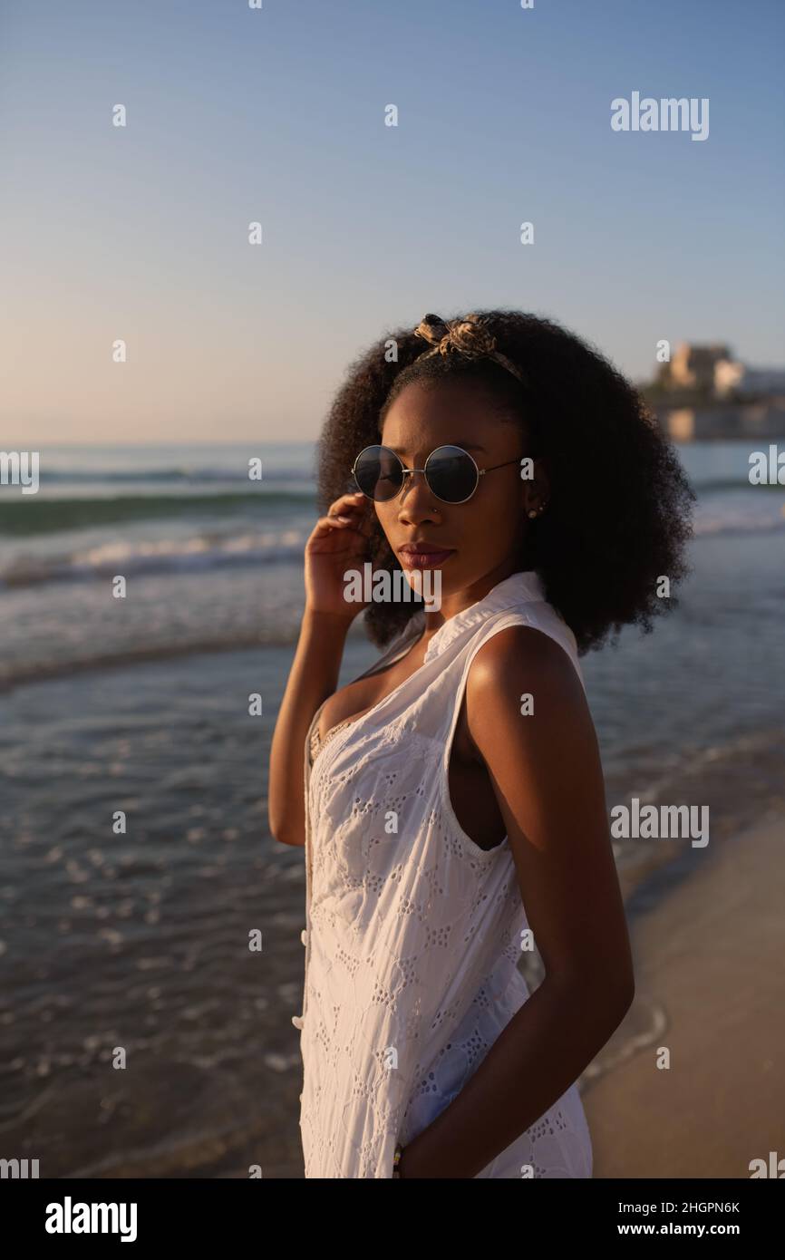 Young adult woman in the beach posing and looking at camera at sunset Stock Photo