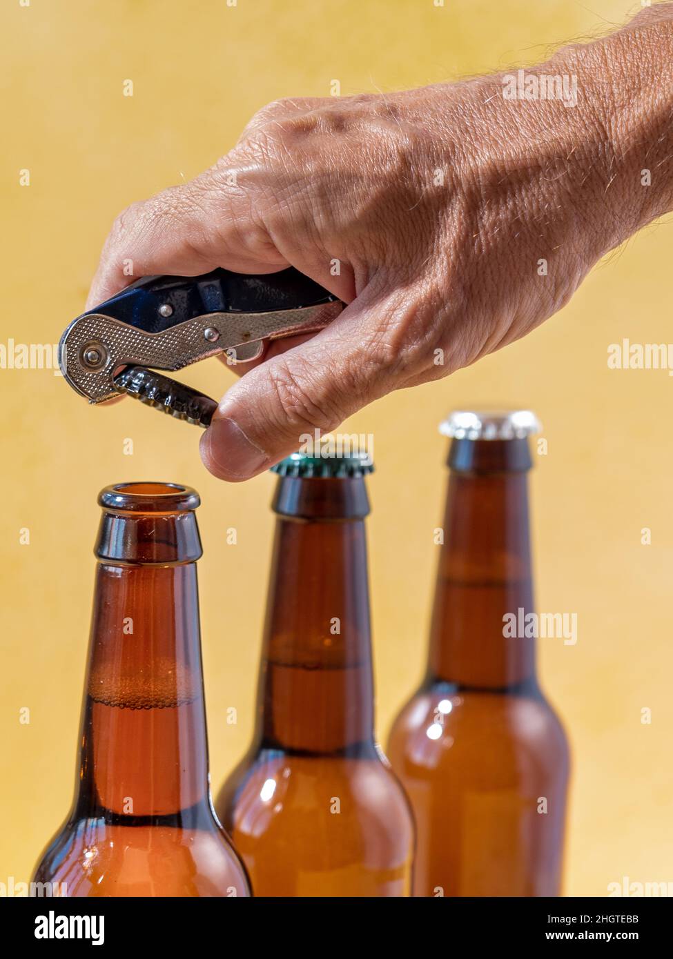 Hand opening beer bottle with blurred background Stock Photo