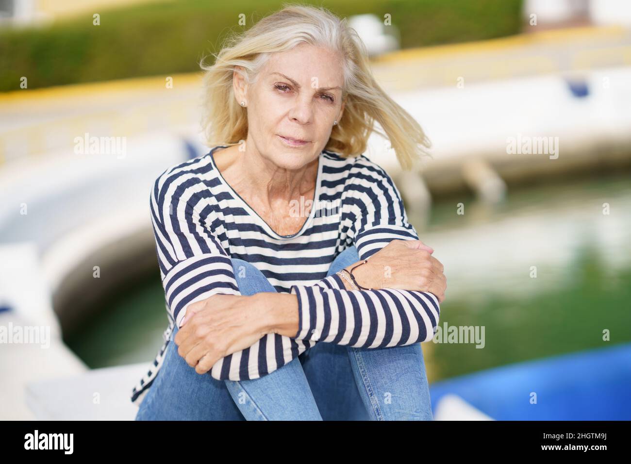 Eldery woman looking serenely at the camera, sitting in a seaport Stock ...