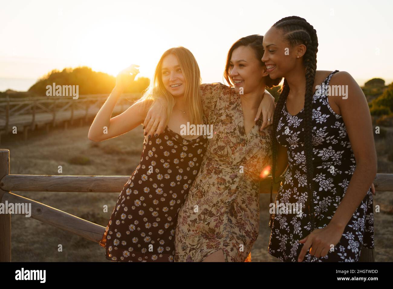 Smiling diverse women embracing on wooden boardwalk Stock Photo