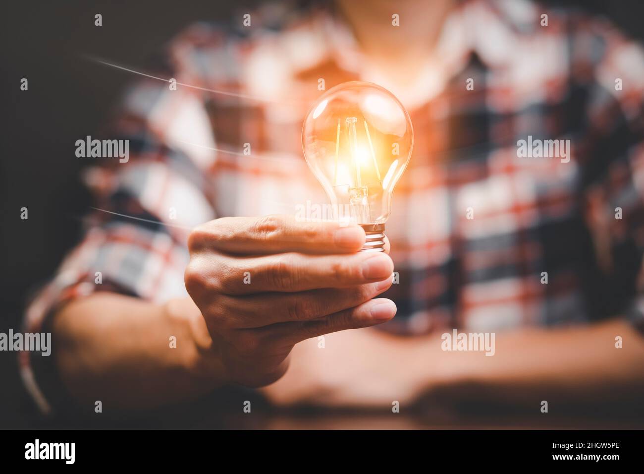 Man hand holding light bulb with line connect and working on the desk ...