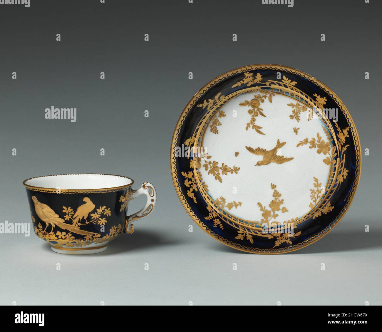 Teacup (one of 8) (part of a service) ca. 1758–69 Chelsea Porcelain Manufactory The gilding on these pieces (see 54.163.7a, b–.34) is of a very high order, with tooled work on a thick application of honey gilding selectively matte and burnished for a lively design of pheasants, peacocks, and swallows in a landscape. The deep bowl was for little cakes.. Teacup (one of 8) (part of a service). British, Chelsea. ca. 1758–69. Soft-paste porcelain. Chelsea Porcelain Manufactory (British, 1745–1784, Gold Anchor Period, 1759–69). Ceramics-Porcelain Stock Photo