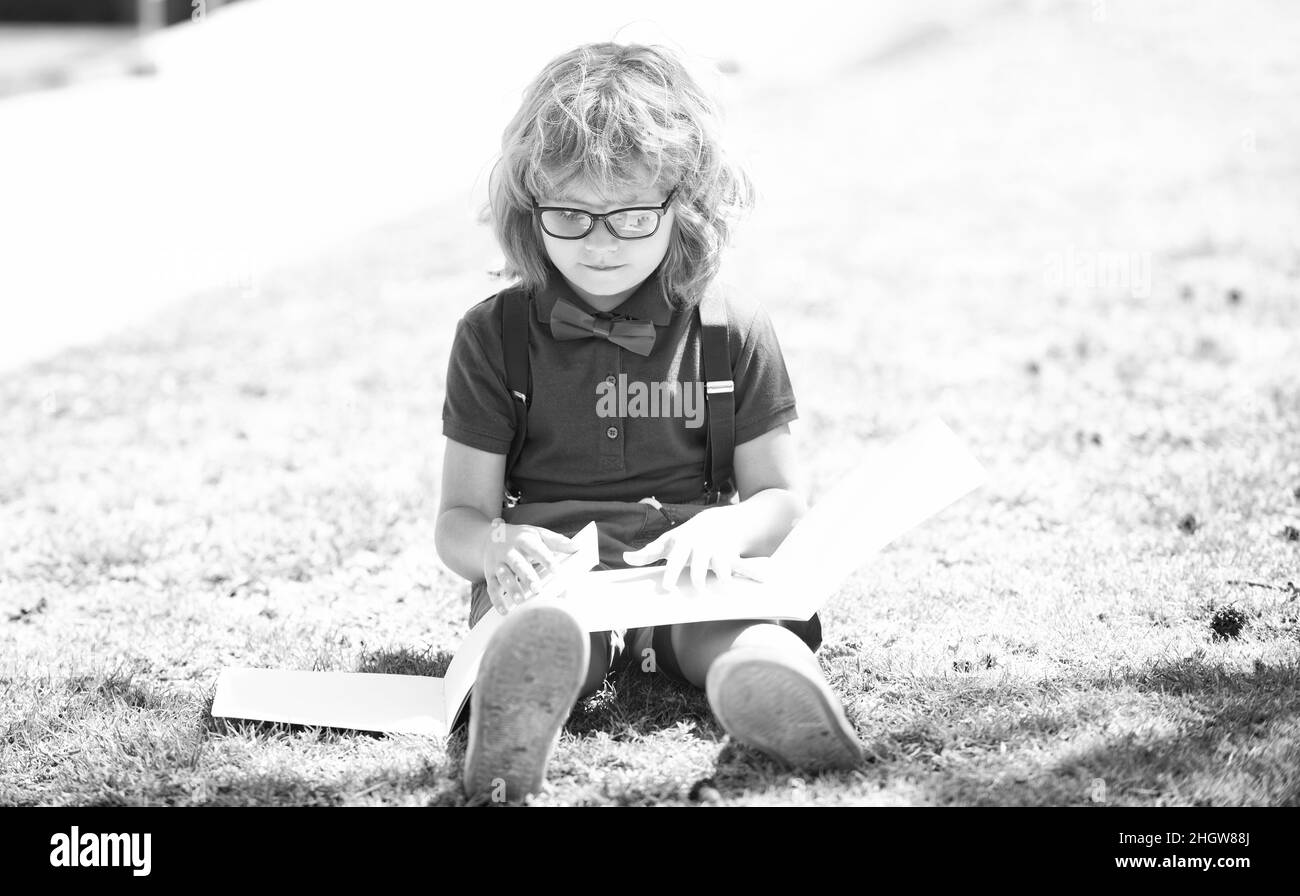 smart curious nerd in glasses reading book study with copybook outdoor, back to school Stock Photo