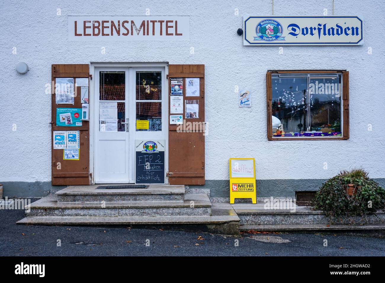 A small corner shop in a village in Wangen, a district of Starnberg, in Bavaria. A black sign announces: FFP2 masks available. Stock Photo