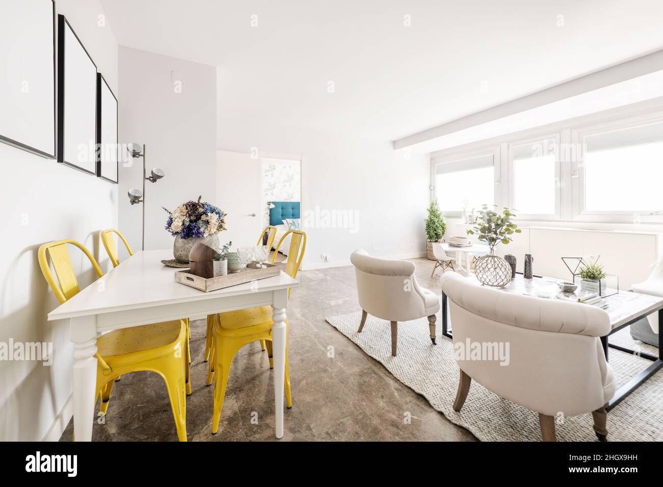 Living room with large window and white dining table with yellow metal