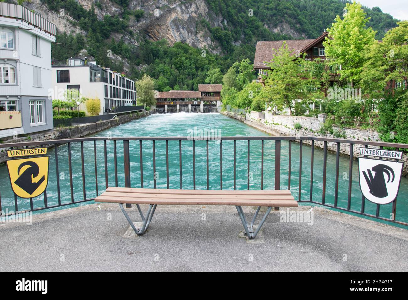 A wooden park bench in the middle of two towns Unterseen and Interlaken on the river with turquoise color Stock Photo