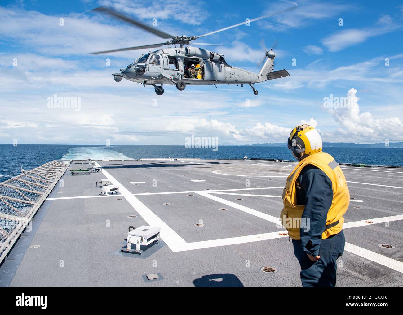 220120-N-PH222-1118 SAN BERNARDINO STRAIT (Jan. 20, 2022)    Mineman 2nd Class Roslin Menotapar, from Bossier City, Louisiana, salutes an MH-60S Sea Hawk Helicopter, assigned to the “Blackjacks” of Helicopter Sea Combat Squadron (HSC) 21, from the flight deck aboard Independence-variant littoral combat ship USS Charleston (LCS 18), during an archipelagic sea lane pass through the San Bernardino Strait, crossing from the Philippine Sea into the South China Sea. Charleston, part of Destroyer Squadron (DESRON) 7, is on a rotational deployment in the U.S. 7th Fleet area of operation to enhance int Stock Photo