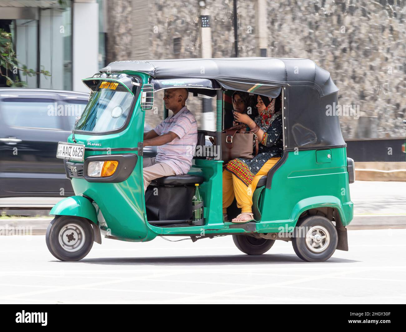 Green auto rickshaw, also called tuk-tuk, with two female passengers, in Colombo, Sri Lanka Stock Photo