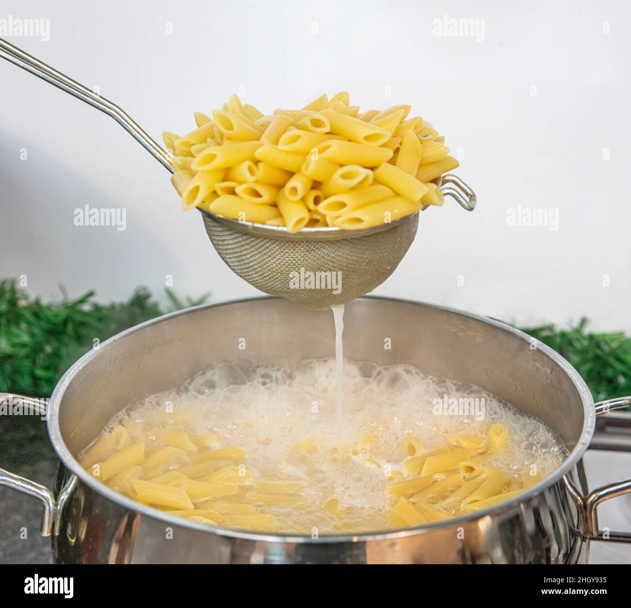 Cooking Pasta pour the penne pasta into a metal pot of boiling water