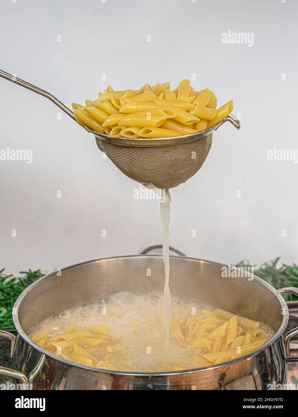 Cooking Pasta pour the penne pasta into a metal pot of boiling water