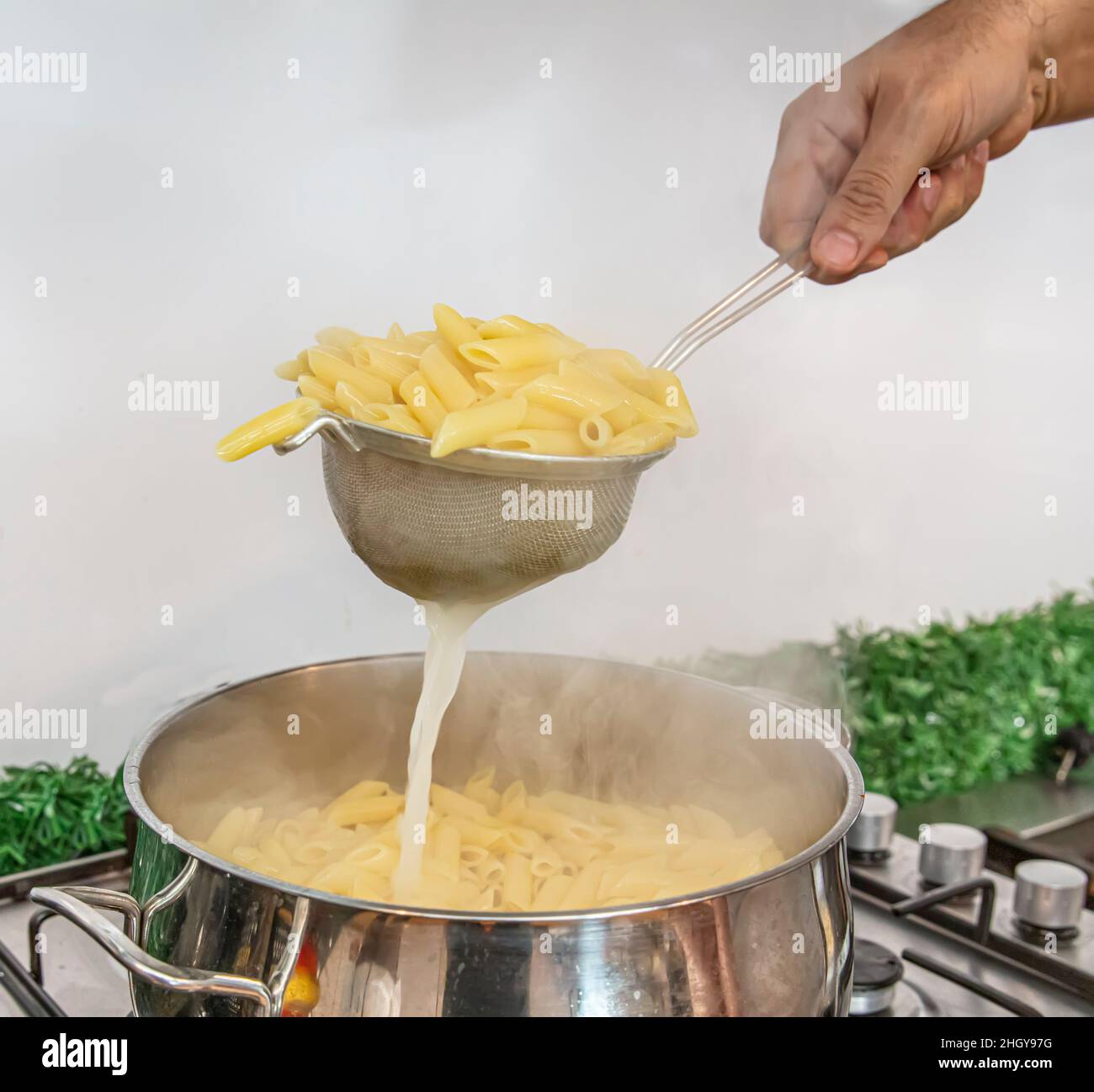 Cooking Pasta pour the penne pasta into a metal pot of boiling water