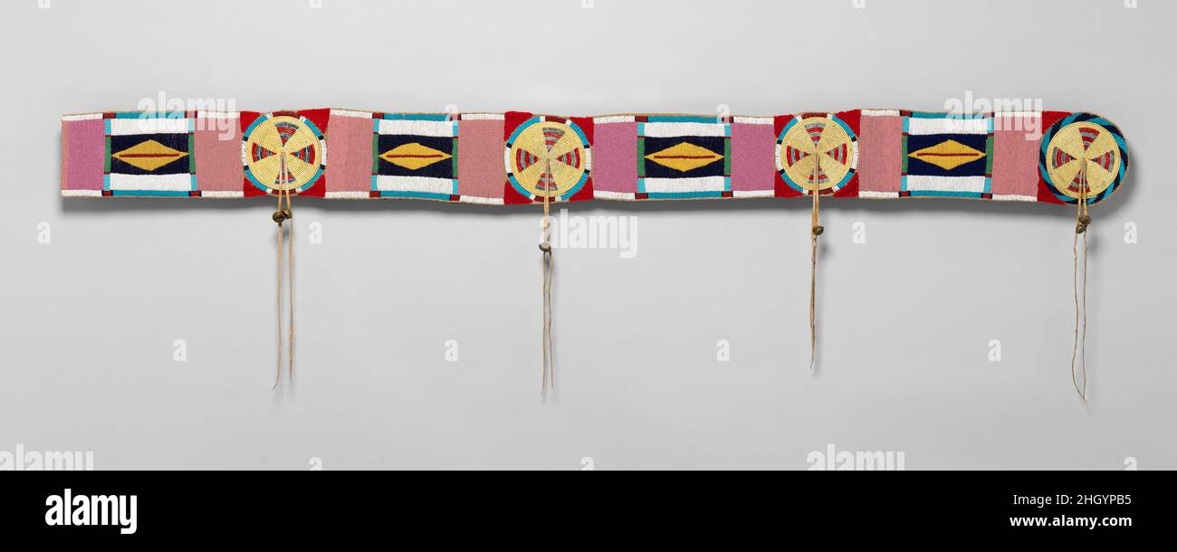 Blanket strip ca. 1850 Niimíipuu / Nez Perce , Native American Blanket strips cover the seam of two sewn-together halves of a bison hide, often used for men’s robes. Born of utility, the strips themselves became symbolic objects. Plains and Plateau men wore them on robes with or without seams, and they later appeared on trade blankets. The rosettes of this rare Plateau strip are constructed of quill-wrapped horsehair.. Blanket strip. Niimíipuu / Nez Perce , Native American. ca. 1850. Tanned leather, glass beads, horsehair, porcupine quills, dye, wool cloth, and brass bells. Possibly made in Id Stock Photo