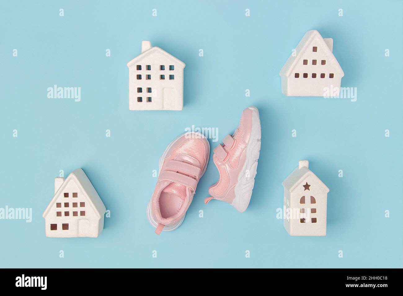 Pink sneakers and white ceramic houses on a blue background. Creative sport concept. Top view Flat lay. Stock Photo