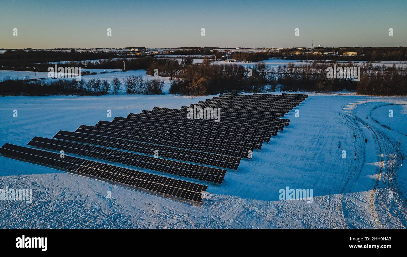 Solar panels being lit up by the setting sun in the winter landscape