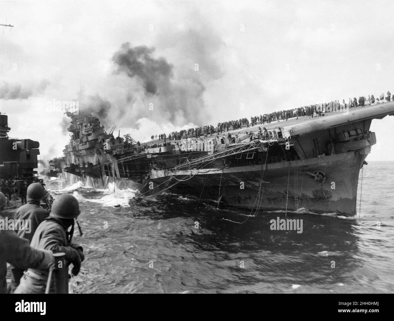 The aircraft carrier USS Franklin listing after being hit by Japnese bombs on the 19th March 1945 Stock Photo