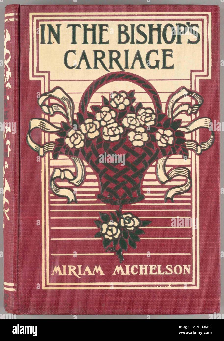 In the bishop's carriage 1904 Margaret Neilson Armstrong "Signed Margaret Armstrong binding design in white and dark green on red buckram of a basket of roses tied with ribbon on either side surmounted by the titles in dark green with a background formed by a "T" shaped white panel with rules of various thicknesses repeated down the stem of the "T". The spine has the titles in dark green and a motif of crossed trumpets decorated with ribbon surmounted by a smiling mask with a double white rule at the head and tail. In original paper dust jacket with the titles in brown on the front and spine p Stock Photo