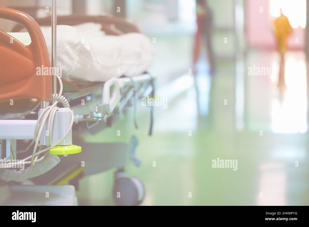 Modern medical bed in the hospital hall on the background of walking people. Stock Photo