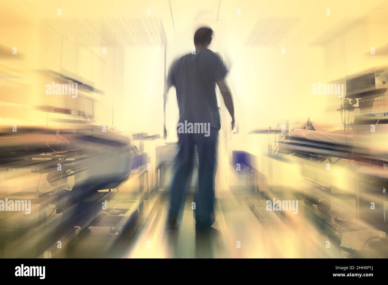 Male doctor figure surrounded by blurred equipment in the hospital room, unfocused background. Stock Photo