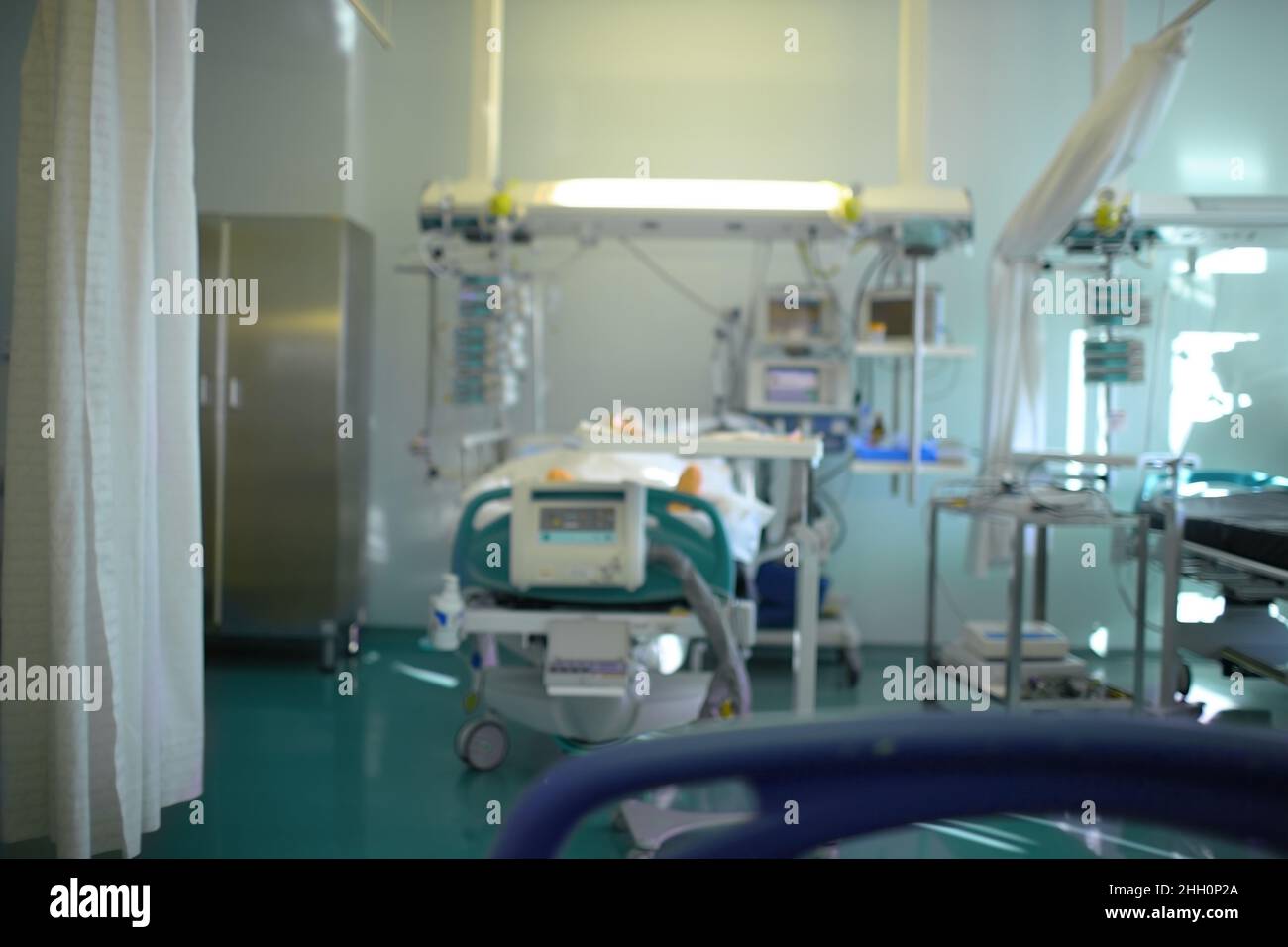 Unconscious patient in the ICU under the clock surveillance, unfocused background. Stock Photo