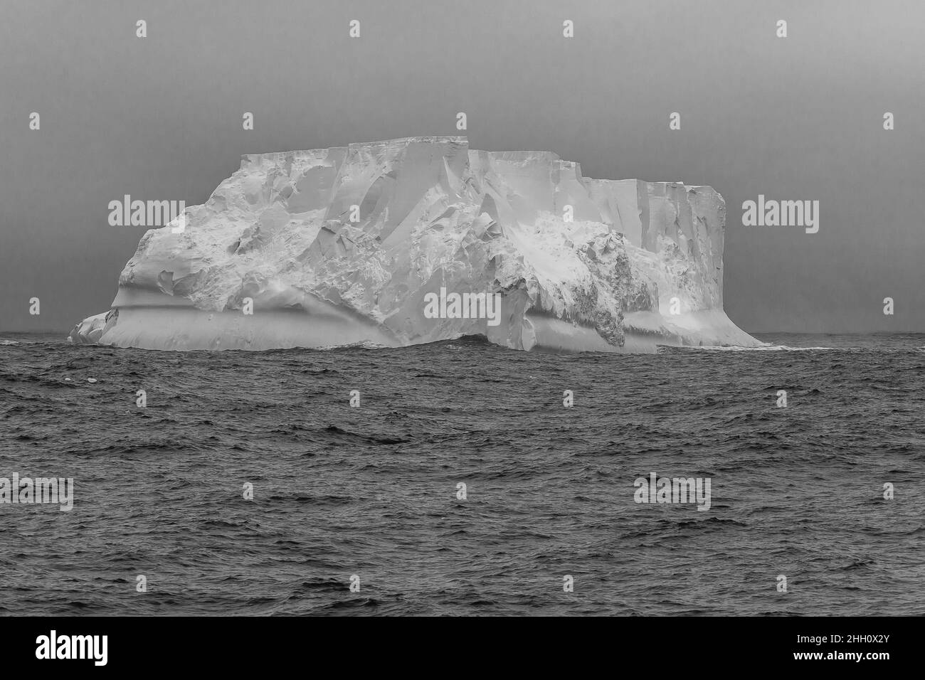 A massive tabular iceberg looms out of the mist having calved from the Mertz or Ninnis glacier. Stock Photo