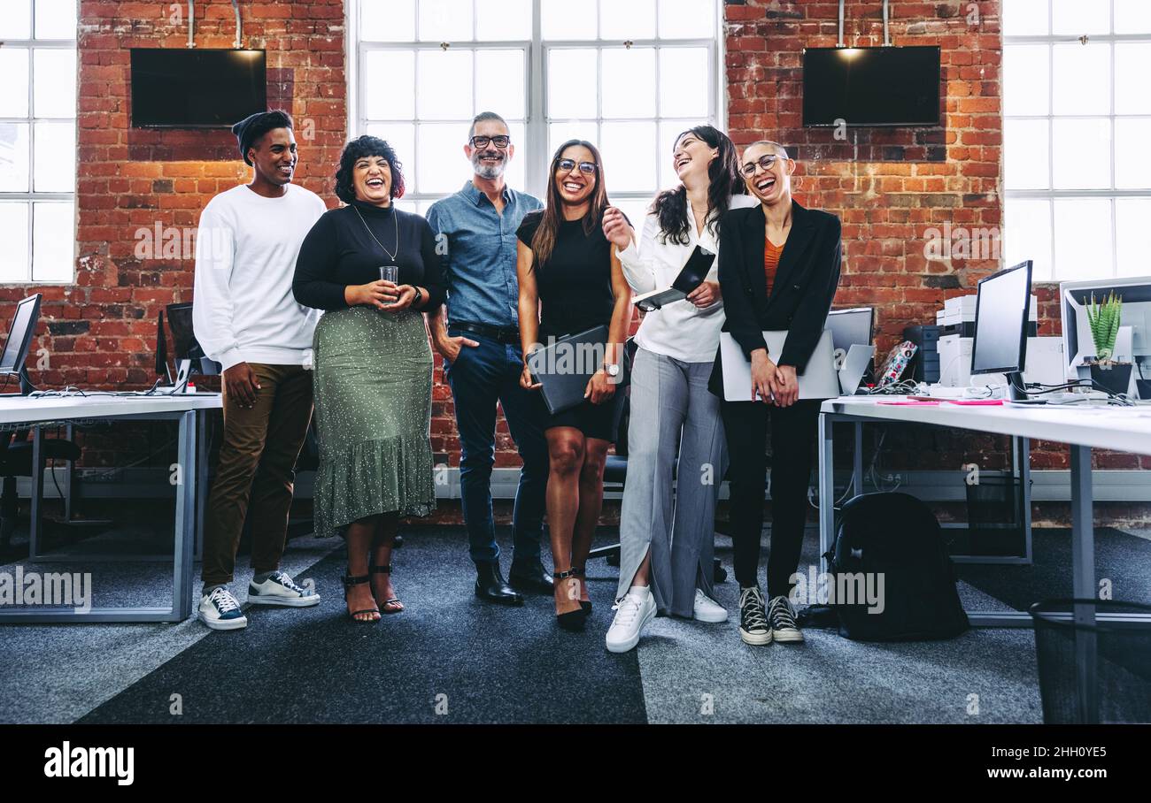 Group of businesspeople laughing cheerfully in a modern workplace ...
