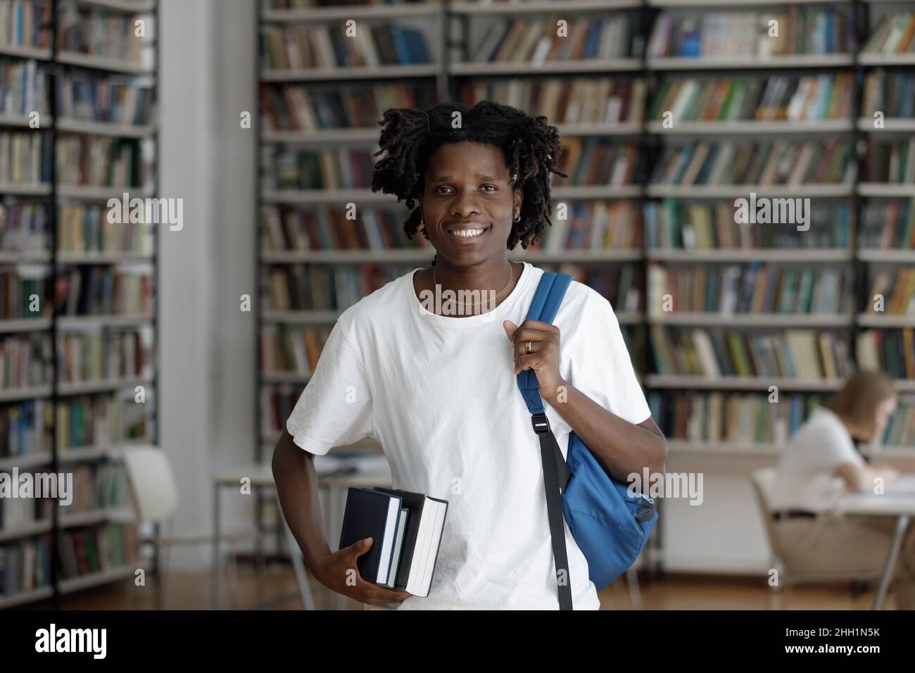 Happy African American student guy with dreads in college library Stock Photo