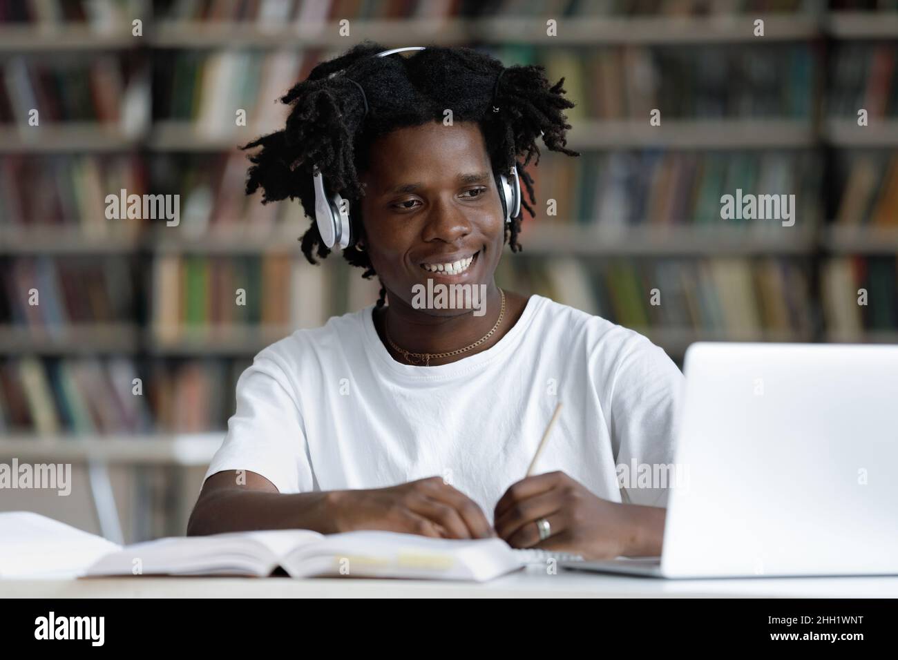 Happy African student guy in headphones watching learning webinar Stock Photo