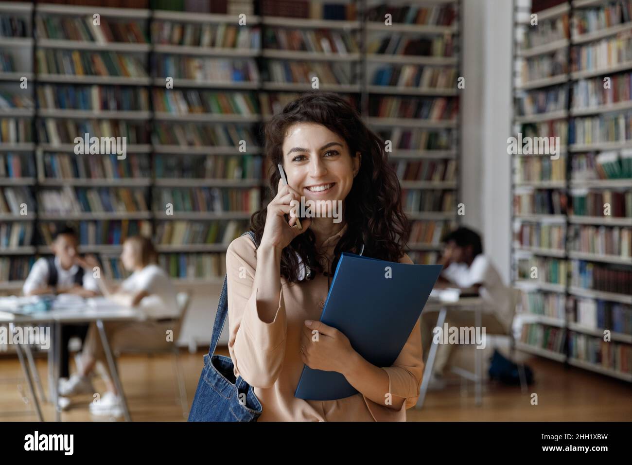 Happy college student talking on mobile phone in university library Stock Photo
