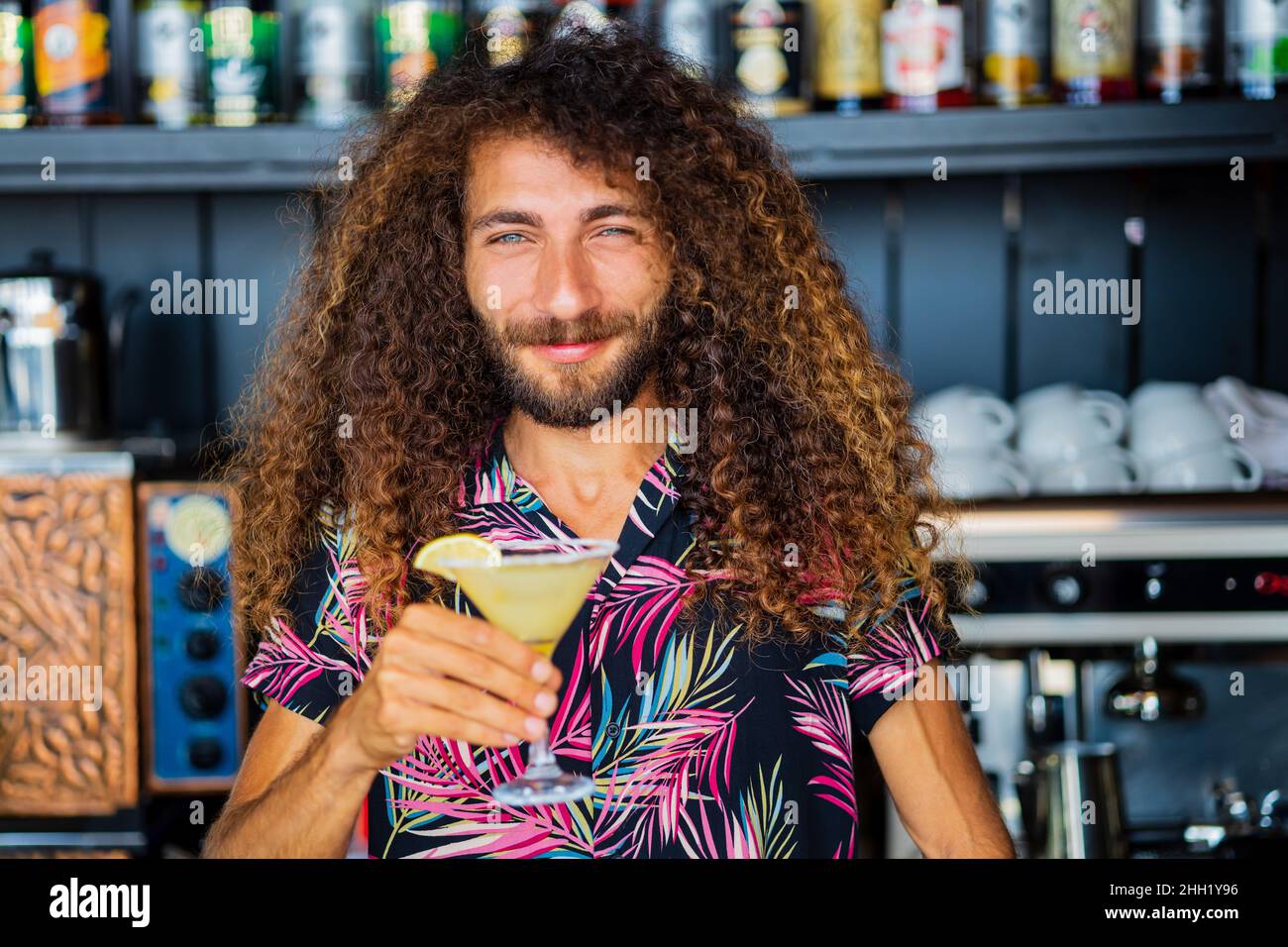 long curly haired mixed race man barman making beverage alcoholic drink at beach shack in tropic Stock Photo