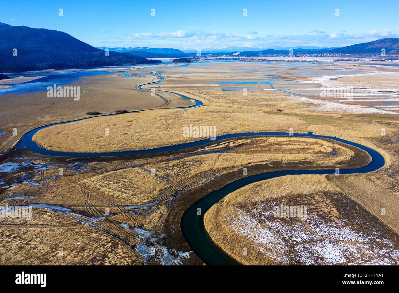 Top aerial view of tributary that flows into Cerknica Lake, beautiful view over the frozen intermittent lake and mountains, taken by drone, Slovenia Stock Photo