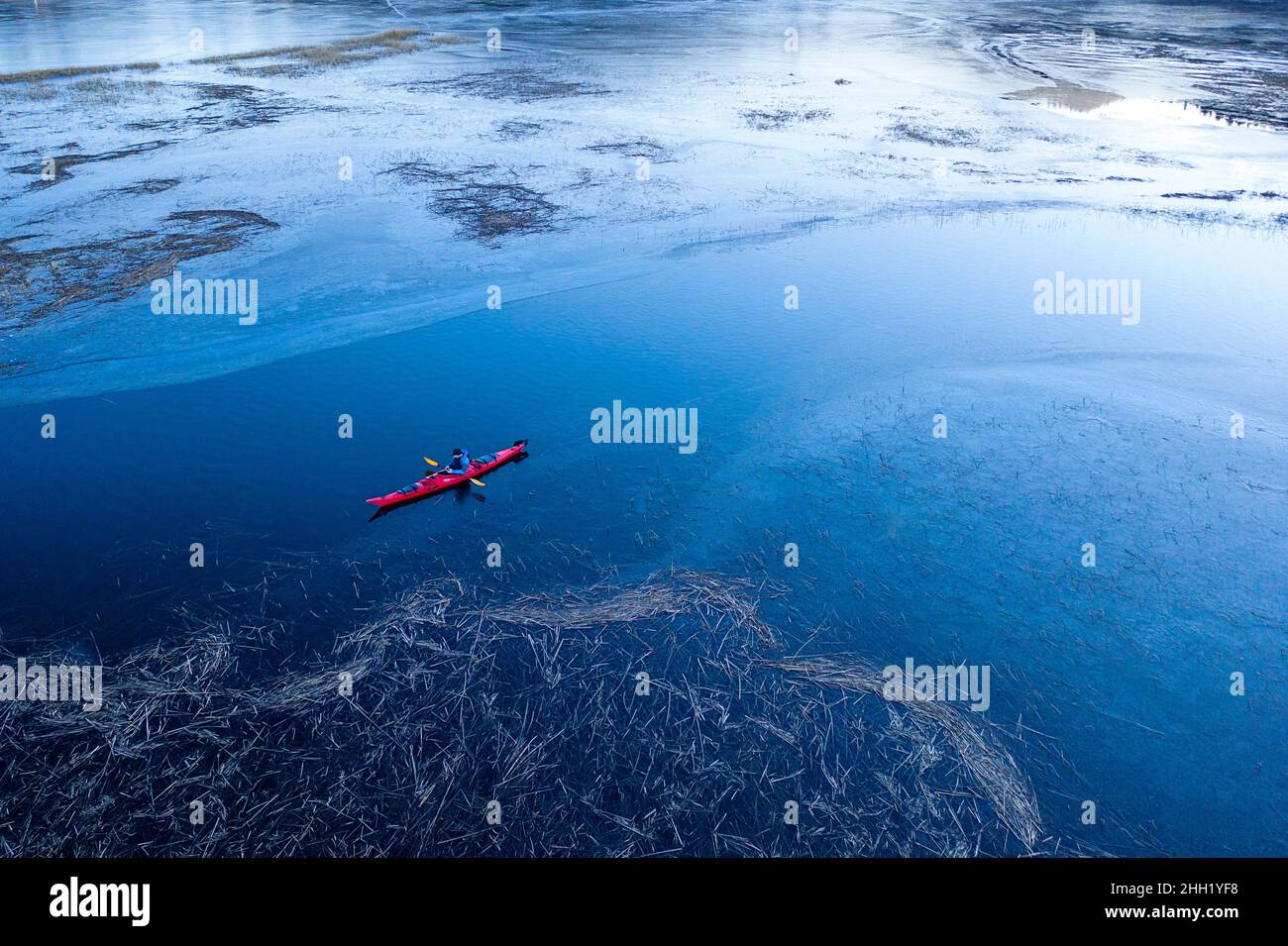 Aerial view of kayaker kayaking on semi frozen intermittent lake Cerknica, with interesting patterns and different hues of blue,Slovenia Stock Photo