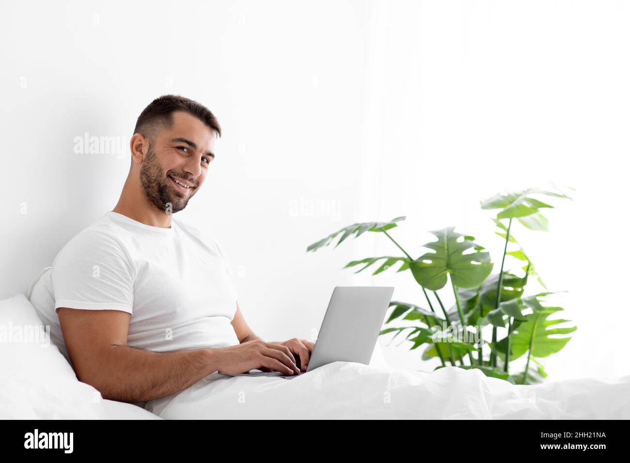 Smiling millennial attractive male manager with beard works on computer Stock Photo