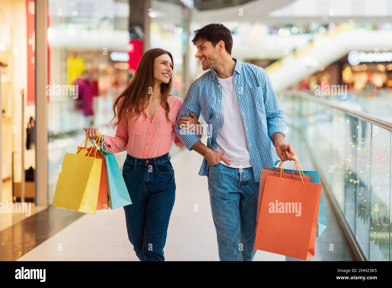Couple Shopping Carrying Shopper Bags Walking In Modern Hypermarket Indoor Stock Photo