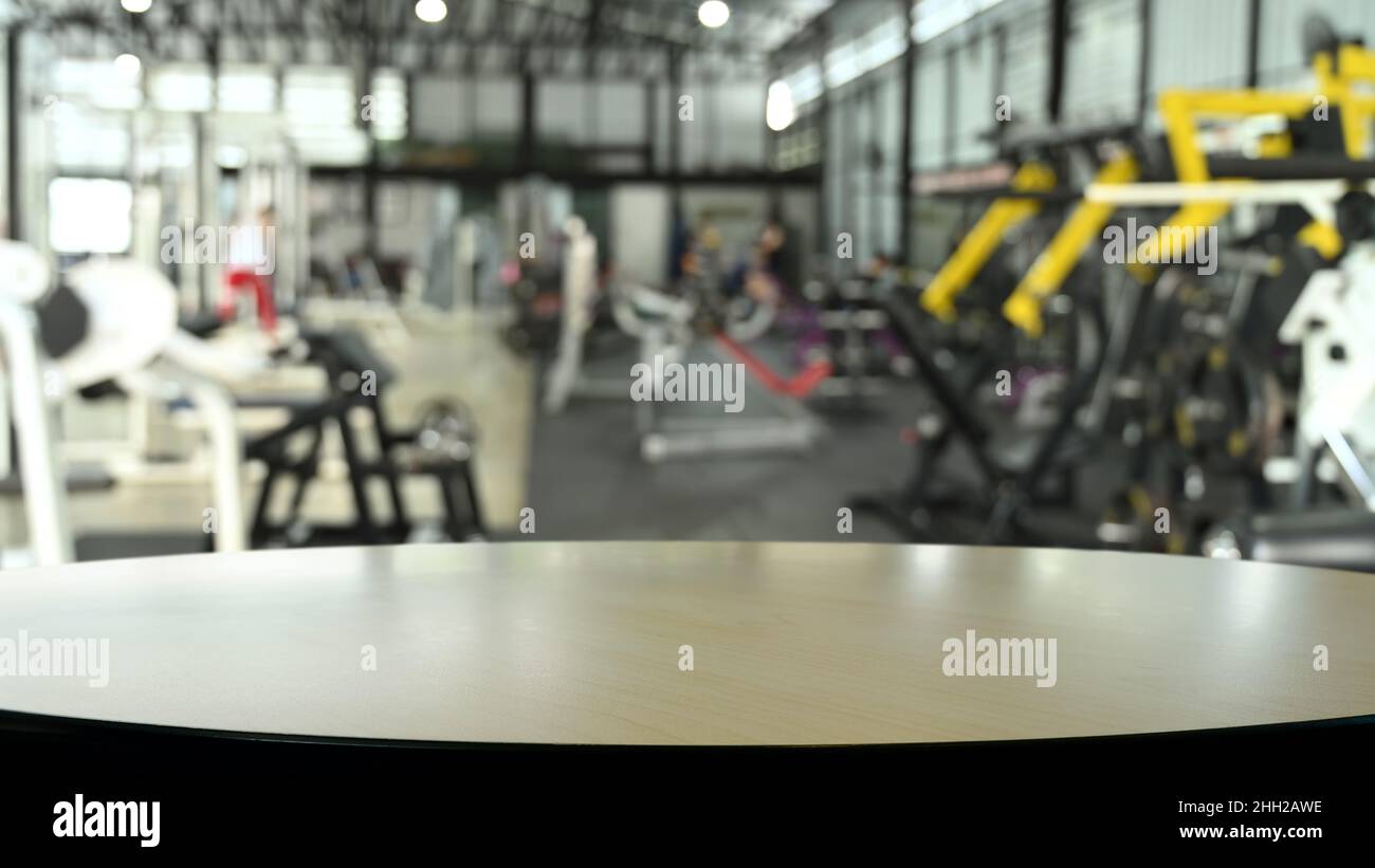 Wooden empty table on blurred background of fitness gym. Copy space for display of product. Stock Photo