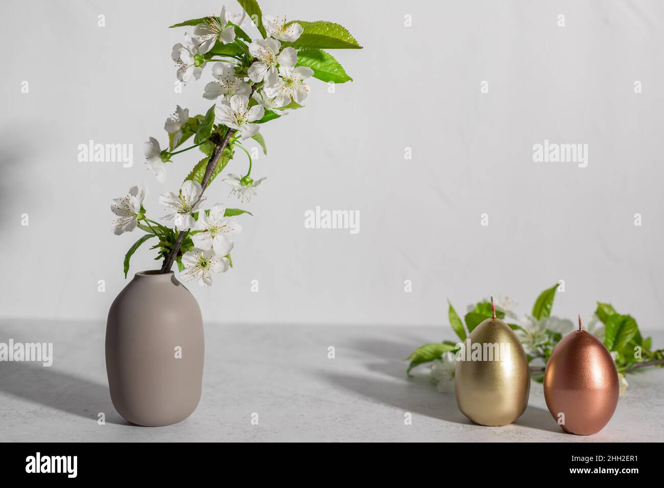 Easter composition with blooming branches and eggs shaped candles Stock Photo