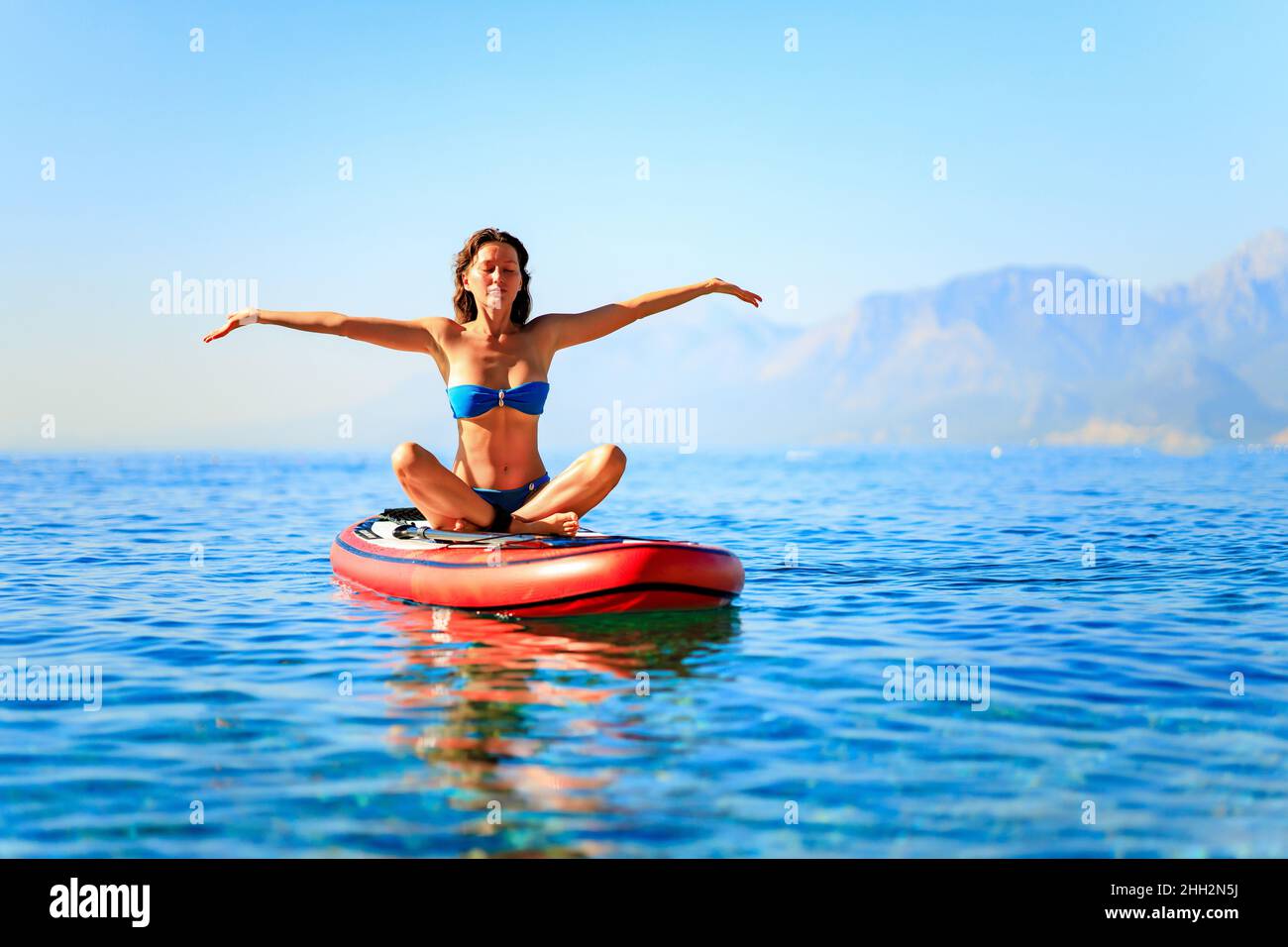beautiful woman practising yoga on paddle sup surfboard Stock Photo