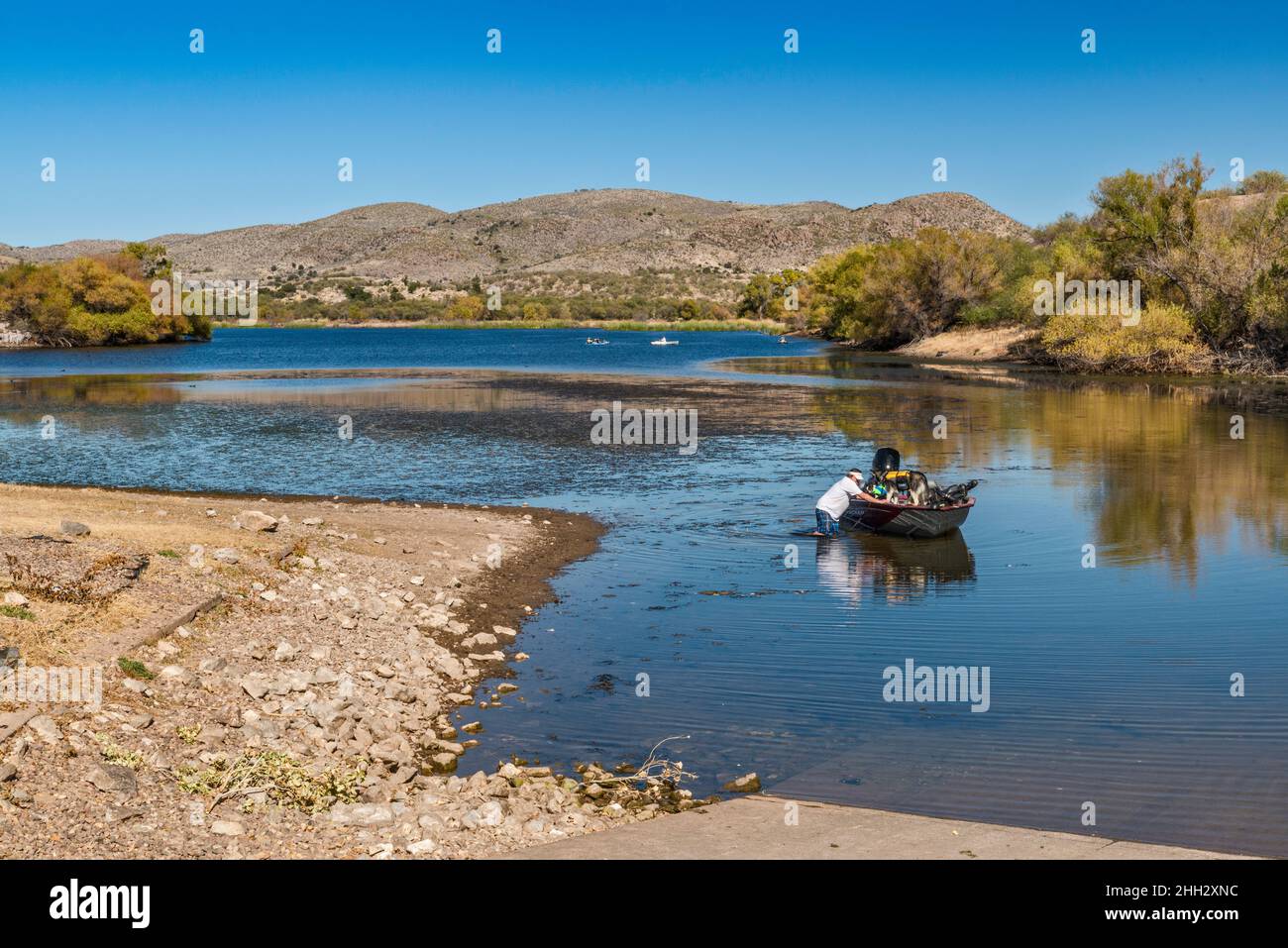 Man wading, pushing speedboat to boat ramp on Arivaca Lake, Atascosa Mountains, Coronado National Forest, Arizona, USA Stock Photo