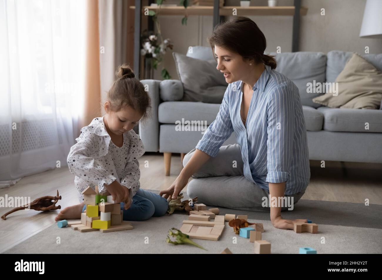 Loving young single mum playing toys with small daughter. Stock Photo