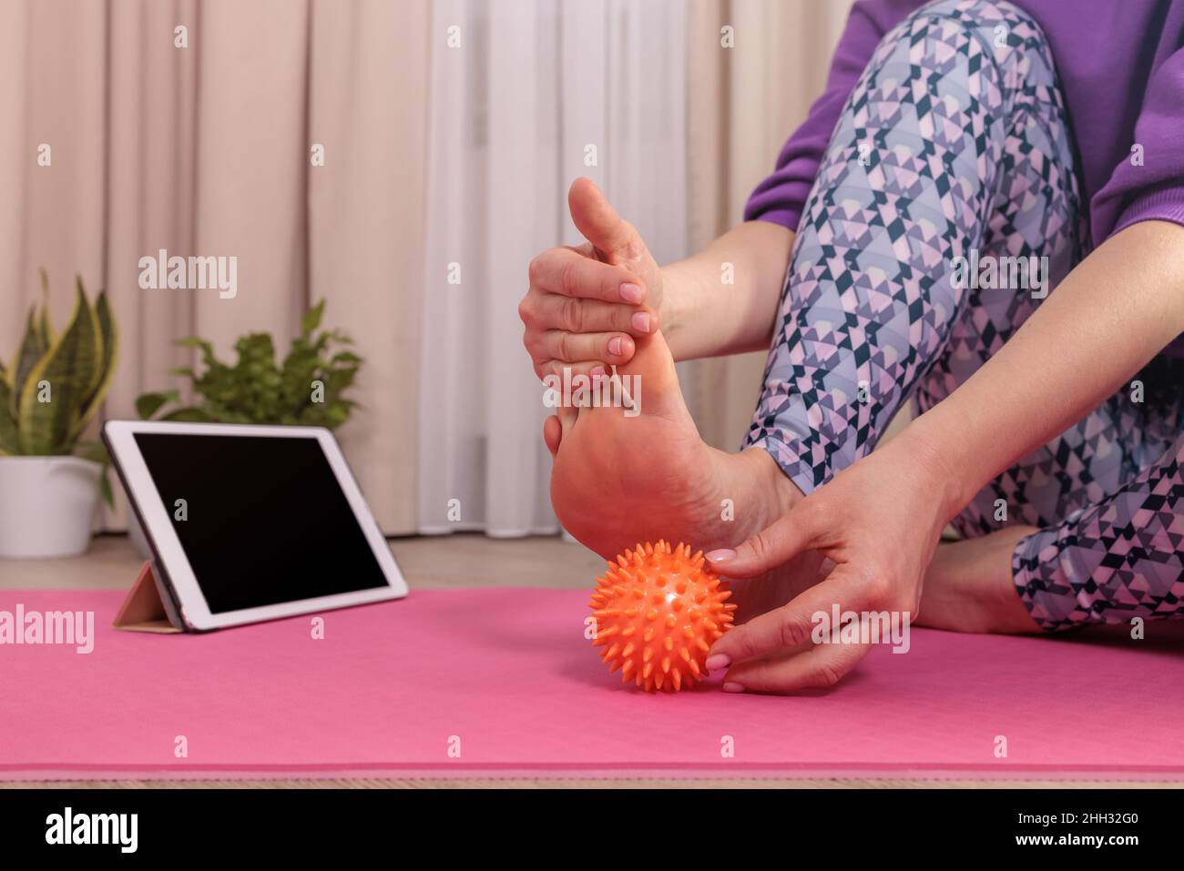girl sits and massages her foot with a prickly ball to relax, looks at