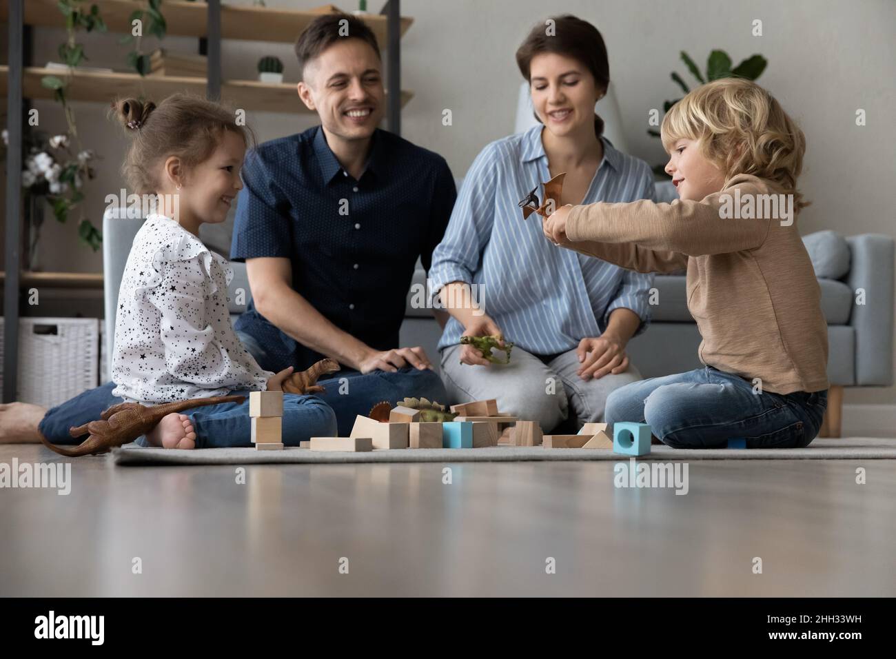 Happy parents playing toys with little children Stock Photo - Alamy