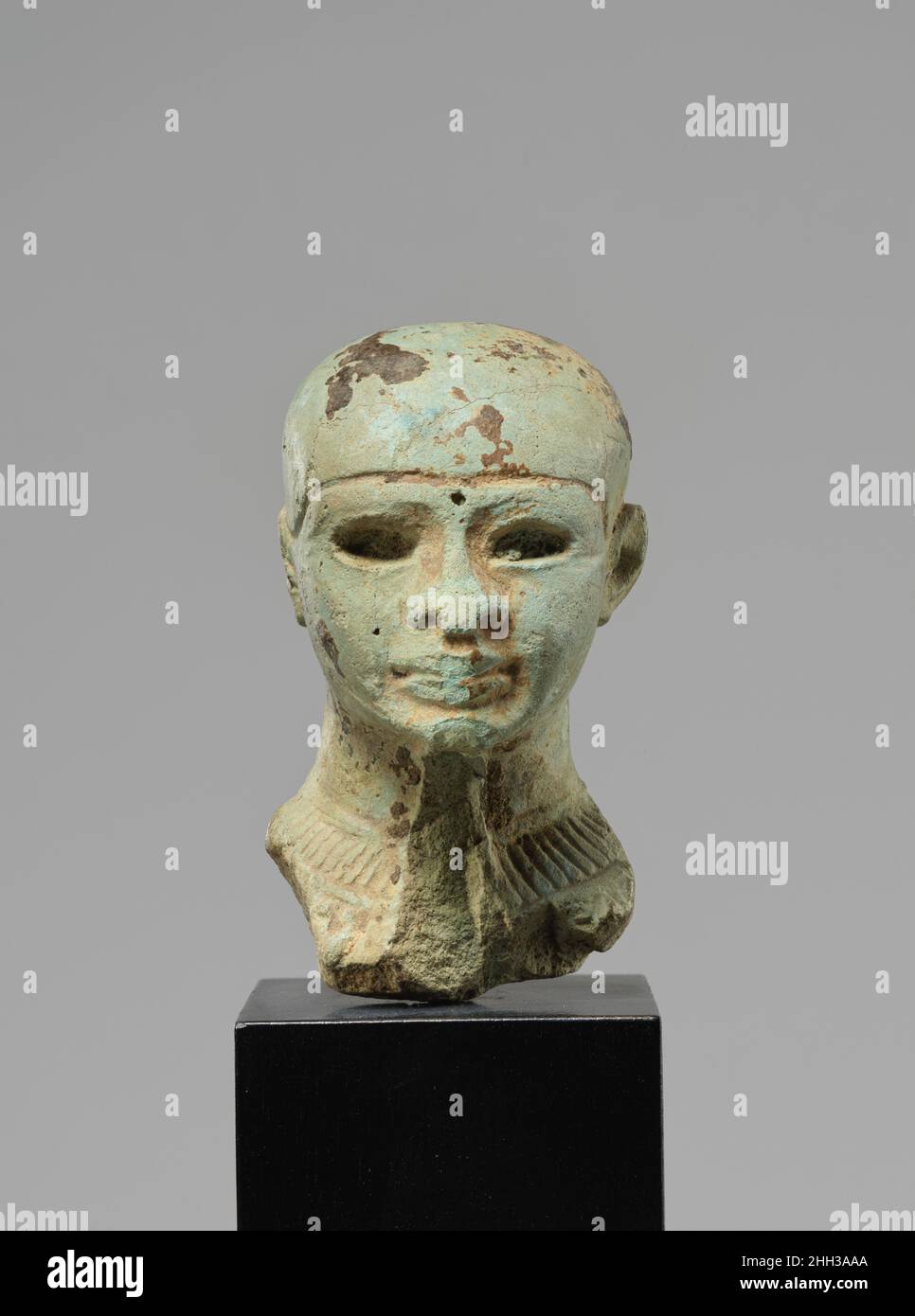 Head of Ptah ca. 1550–1070 B.C. (?) New Kingdom or later The sculpture is a partially preserved head of the god Ptah, made from Egyptian blue with traces of gold leaf on the face. Ptah can be recognized thanks to his close fitting skull cap and (the negative of) his false beard, whose straps can be seen along the jaws. God of the city of Memphis, Ptah was primarily associated with arts and crafts. It is assumed that he acquired his designation as creator god through this close connection with crafstmen, builders, and artists. The gold leaf applied on the face refers to the substance of the div Stock Photo