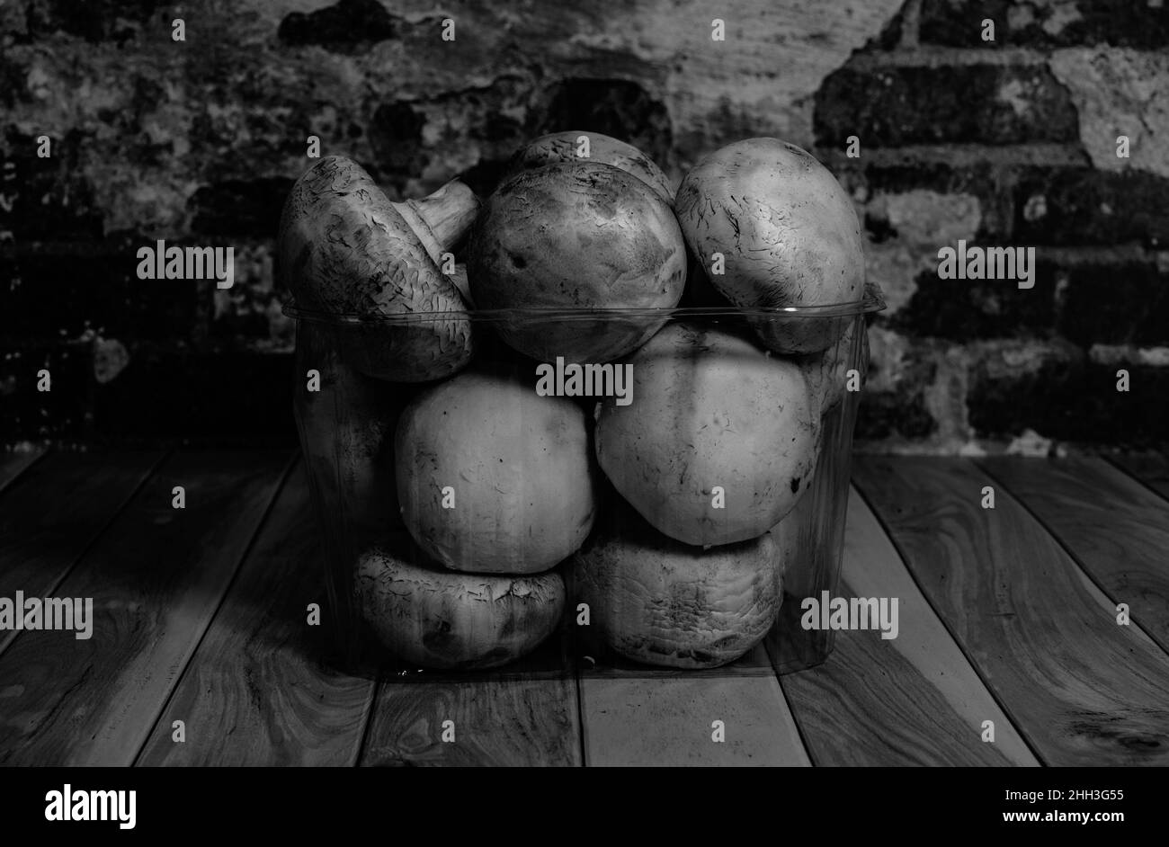 Fresh champignons lie on the table against the background of a brick wall black and white photography close-up Stock Photo